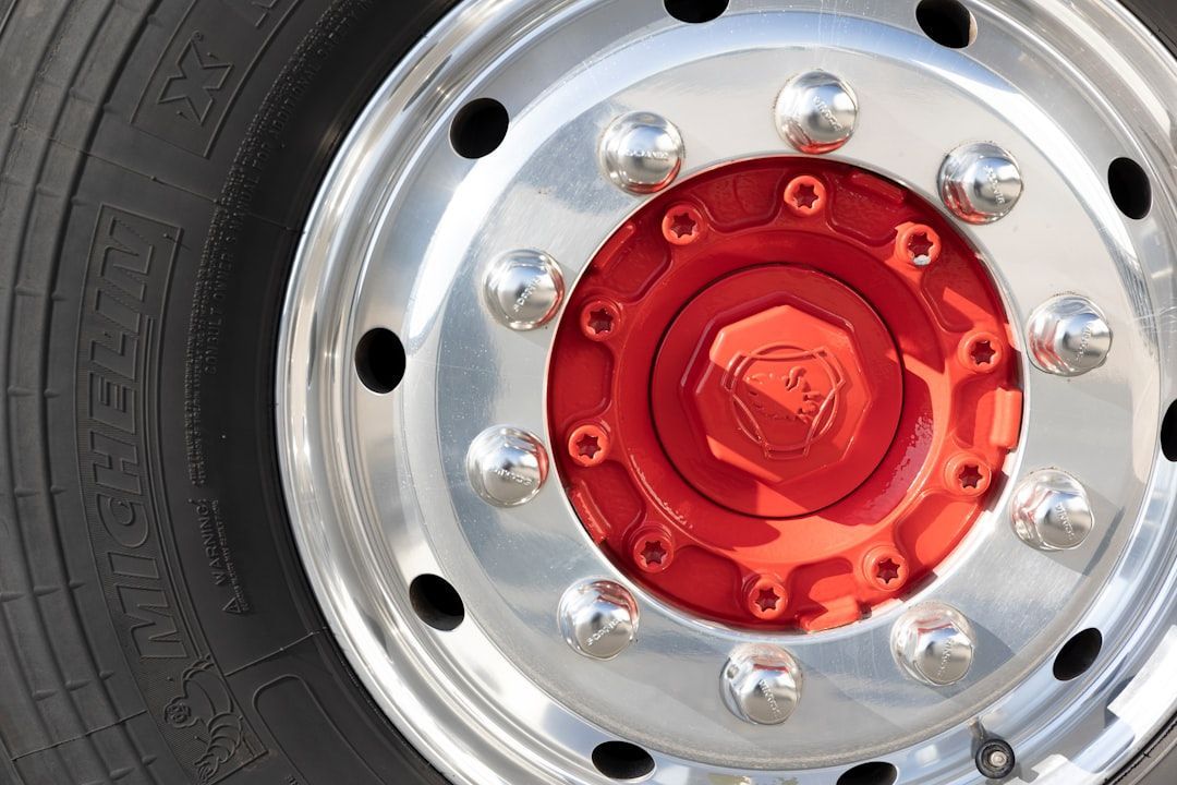 Close-up of a red truck wheel hub with silver rim and lug nuts on a black tire