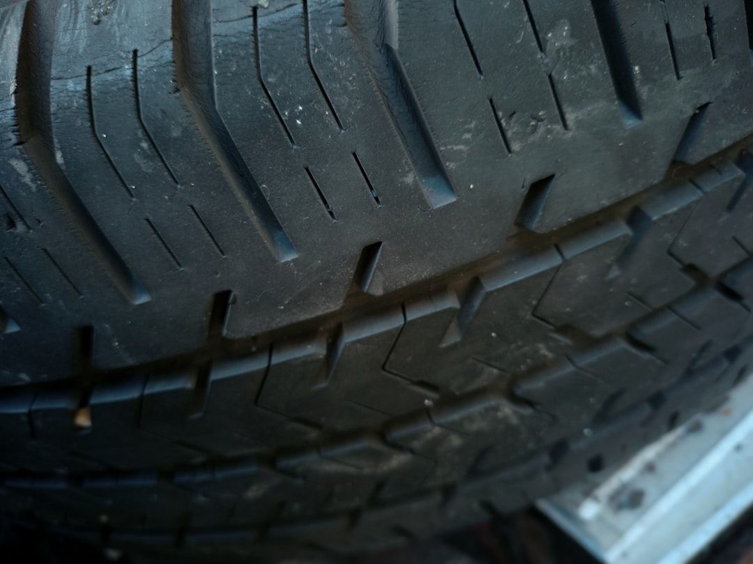 Close-up of a worn car tire tread with visible grooves and a blue-gray rim edge