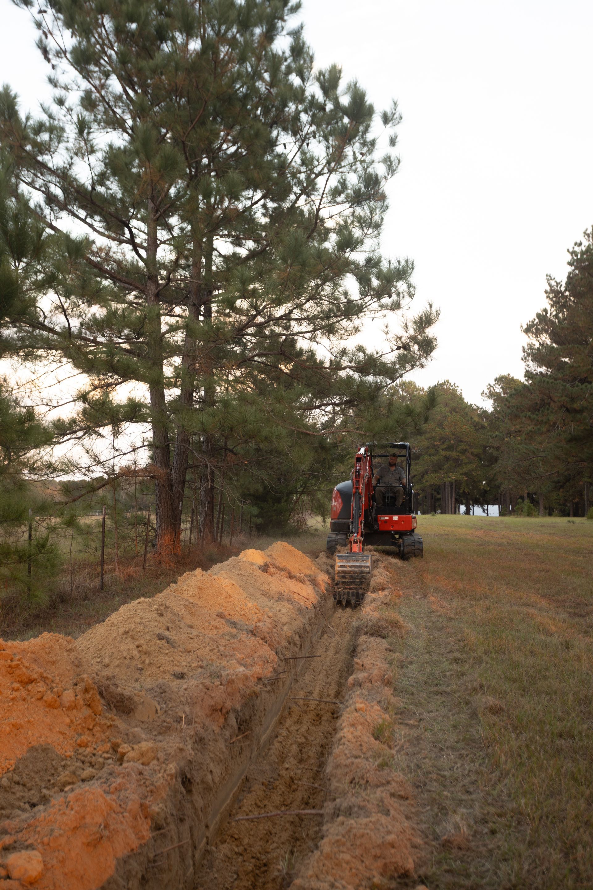 Construction site with muddy ground, blue sky, and a bulldozer.