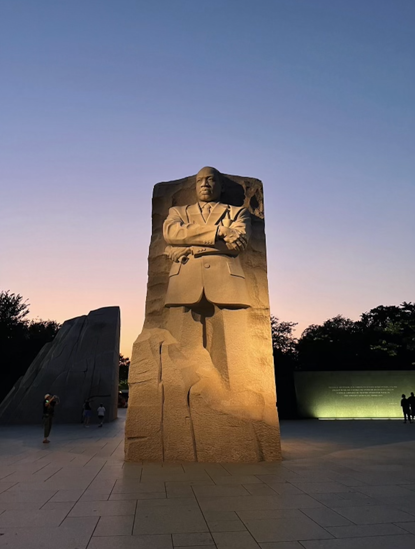 Statue of Martin Luther King Jr., Washington D.C., with the Washington Monument in the background, blue sky.