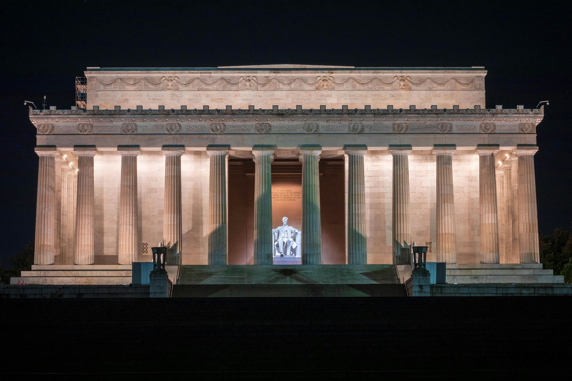 Lincoln Memorial illuminated at night; columns frame the statue of Abraham Lincoln.