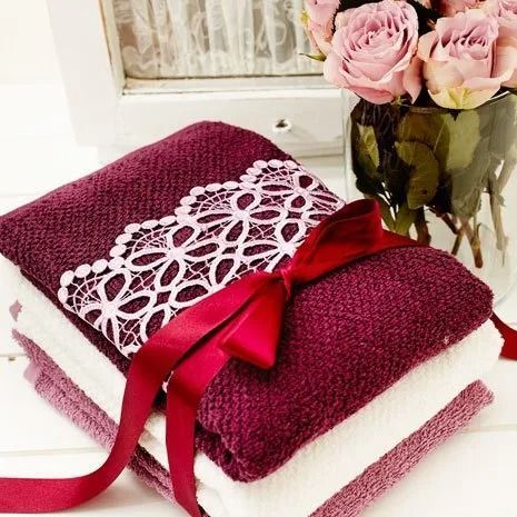 Stack of Purple and White Towels With a Red Ribbon