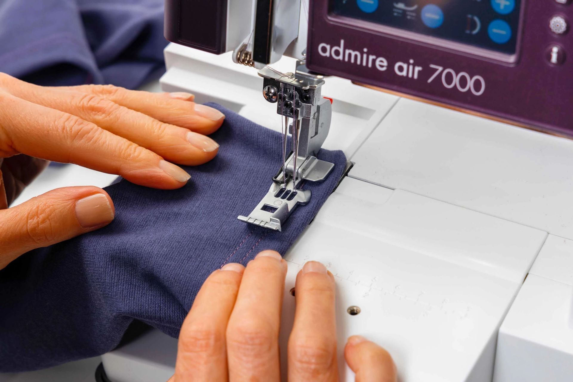 A person is using a sewing machine that says admire air 7000