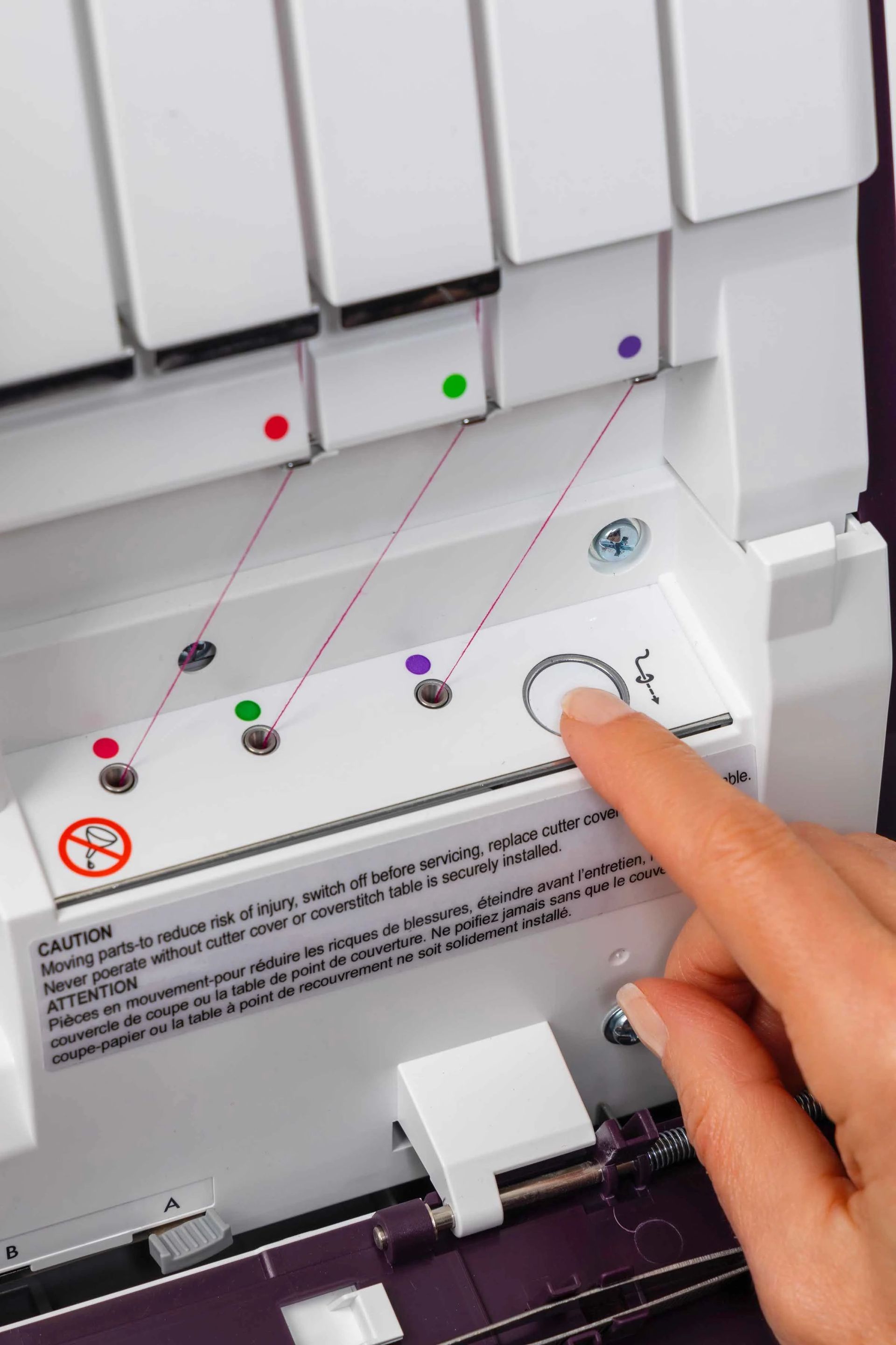 A person is pressing a button on a sewing machine.