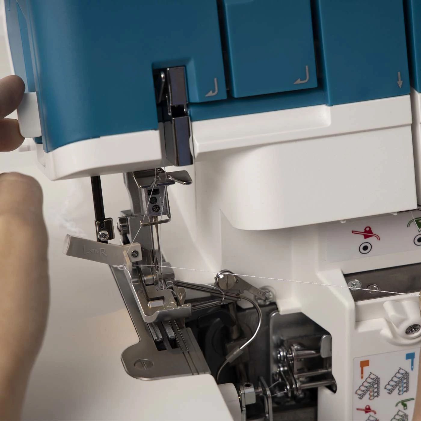 A person is using a blue and white sewing machine
