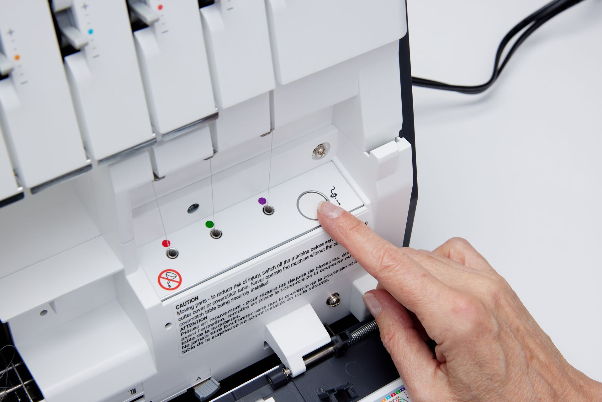 A person is pressing a button on a sewing machine.