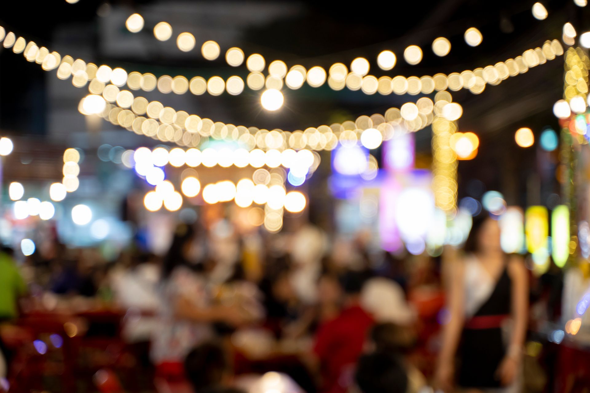 A tractor is rolling asphalt in a parking lot in front of a building.
