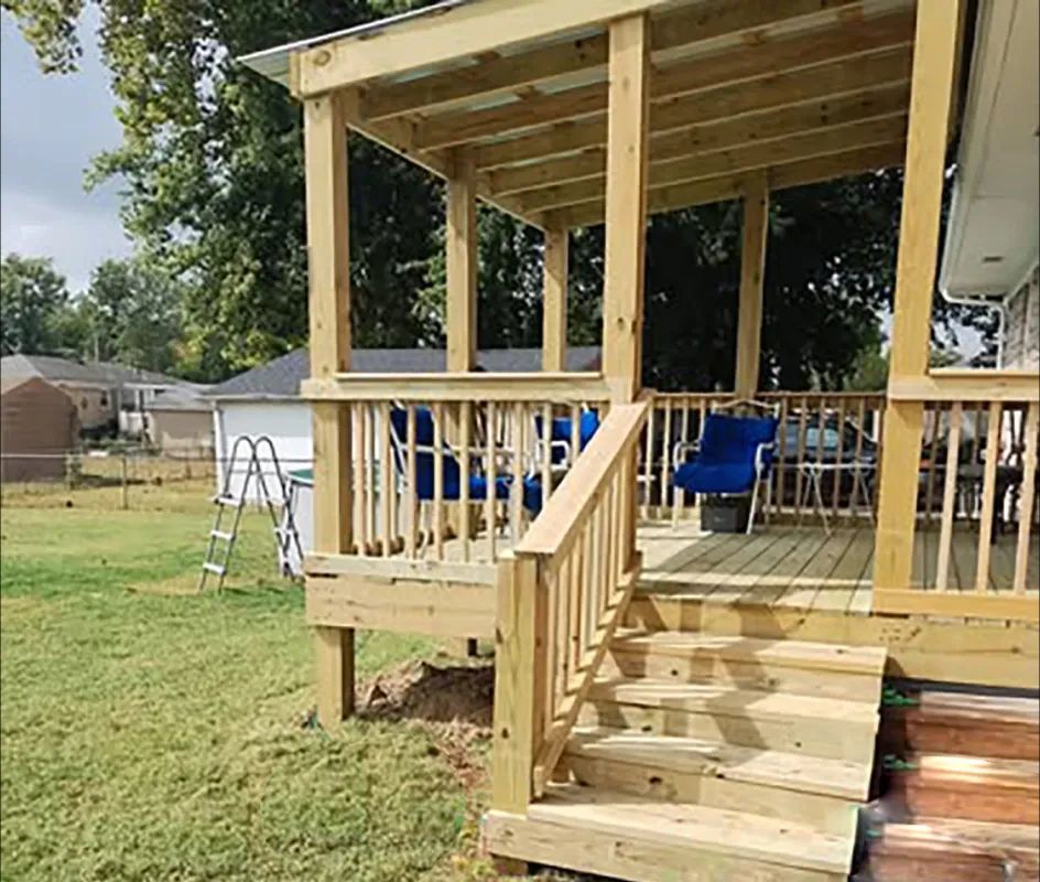 Wooden deck with steps and covered sitting area, blue chairs, backyard setting.