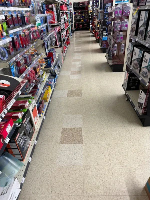 An aisle in a store with shelves of merchandise on either side, well-lit and appearing clean.
