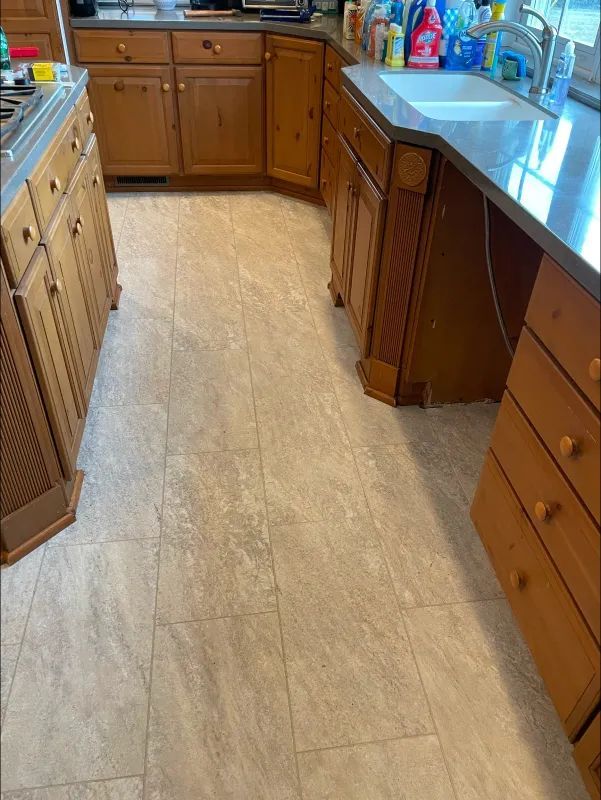Kitchen with light-colored tiled floor, wooden cabinets, countertop, and sink.