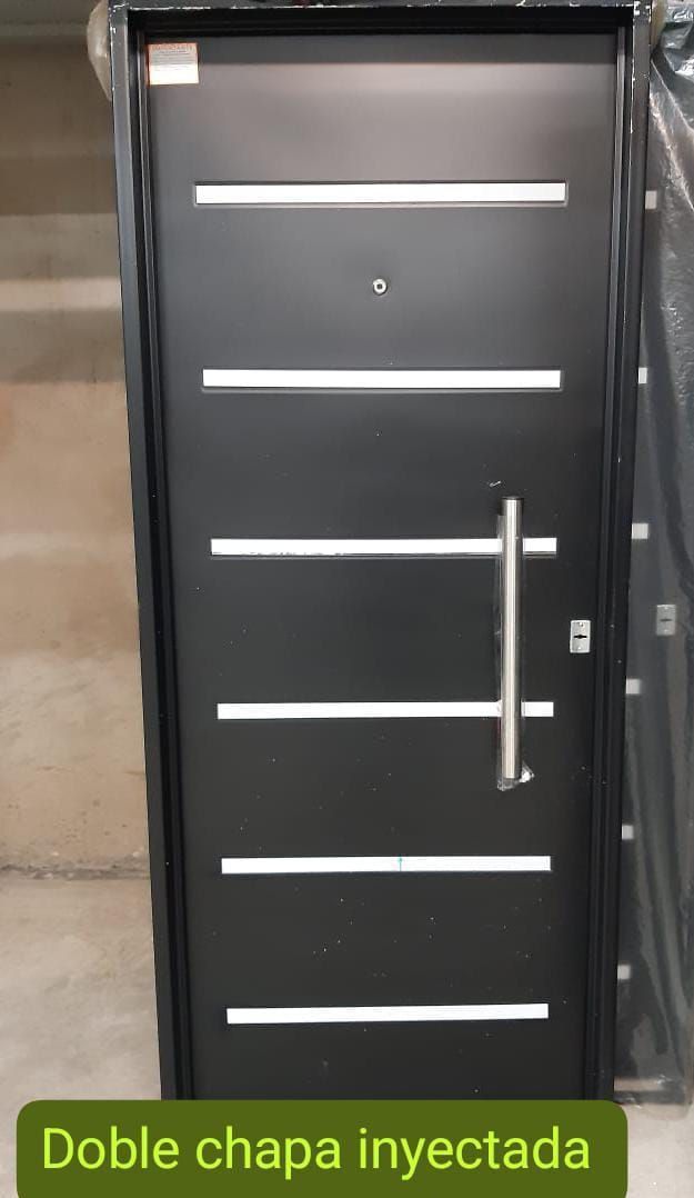 Puerta exterior negra con detalles blancos horizontales y tirador plateado. El texto dice