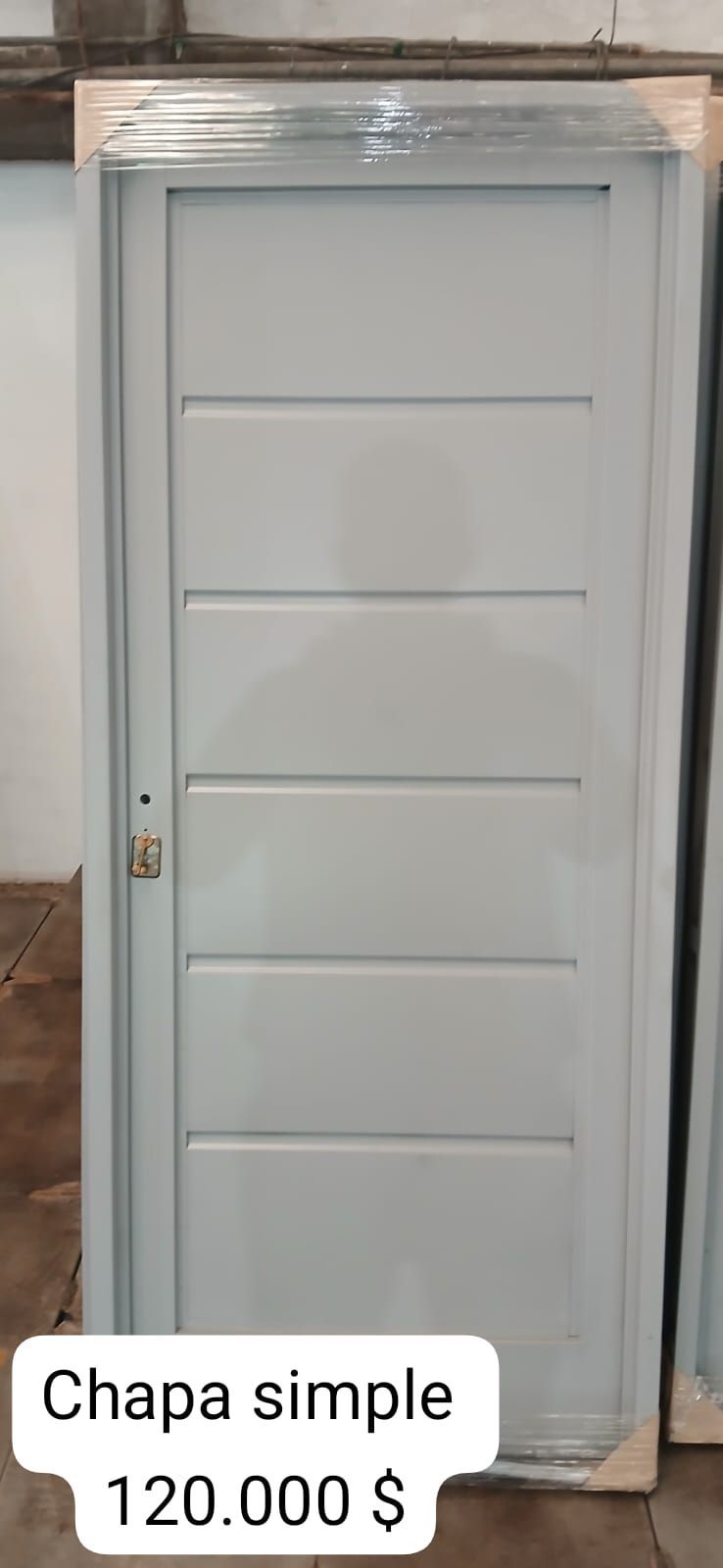 Puerta gris con cinco paneles horizontales. El texto dice