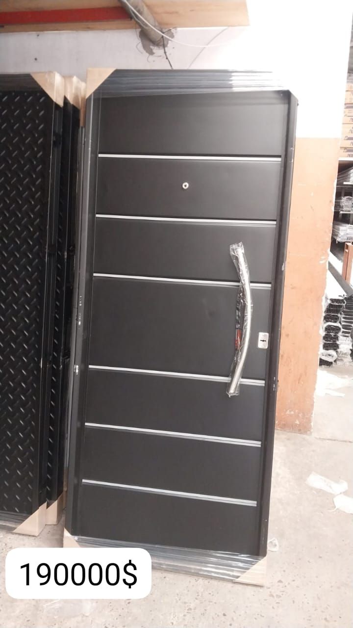 Puerta de metal negra con rayas horizontales plateadas y manija; precio $190000.