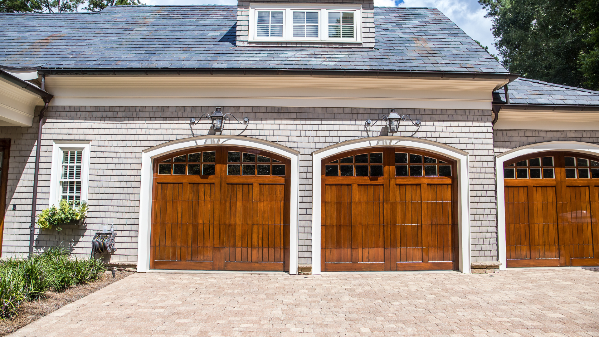 A house with three wooden garage doors and a driveway.