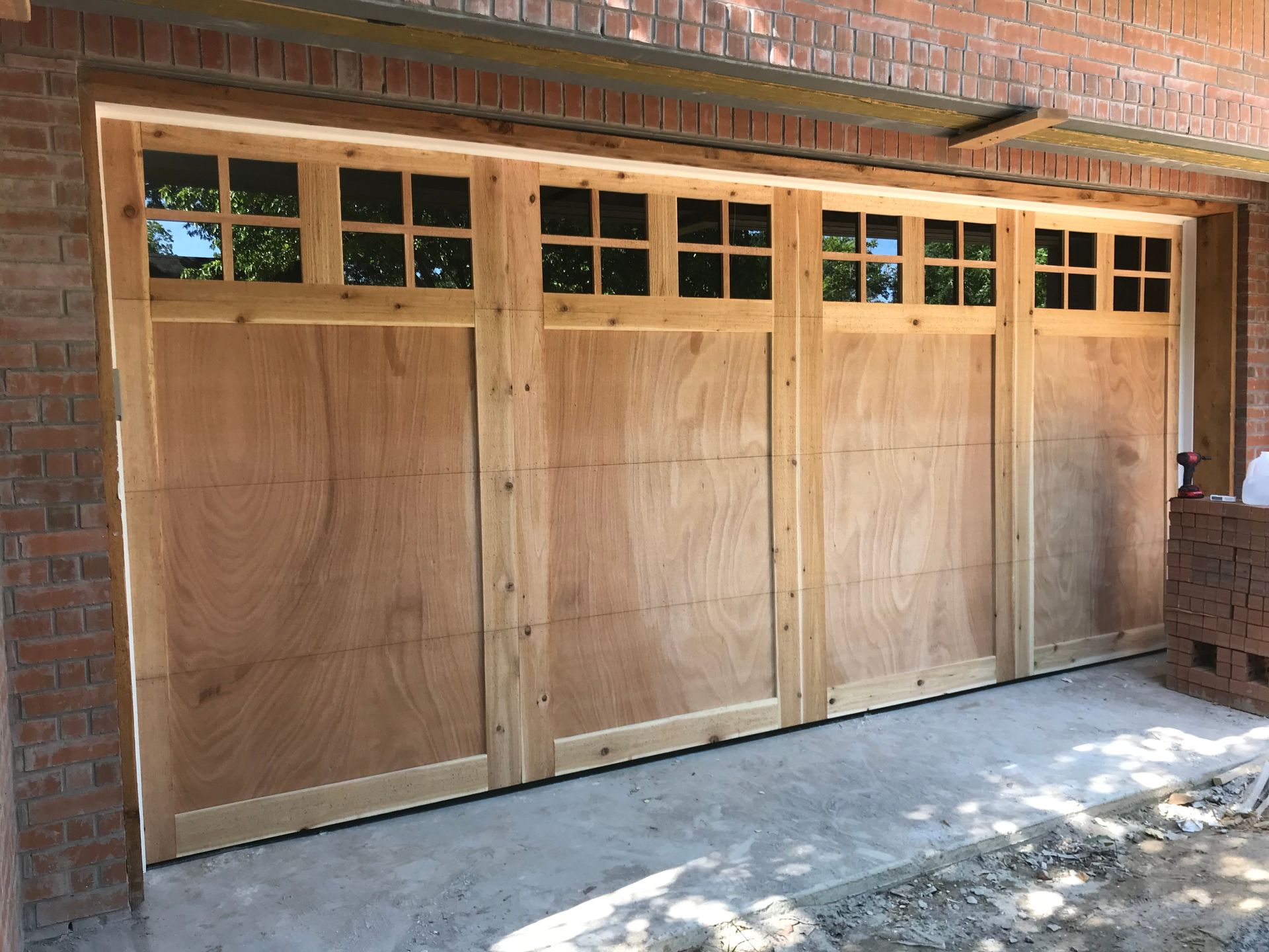 A house with three wooden garage doors and a driveway.