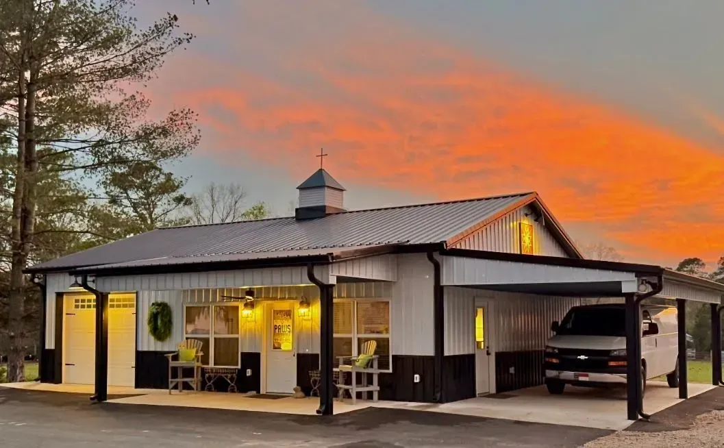 A house with a car parked underneath it and a sunset in the background.