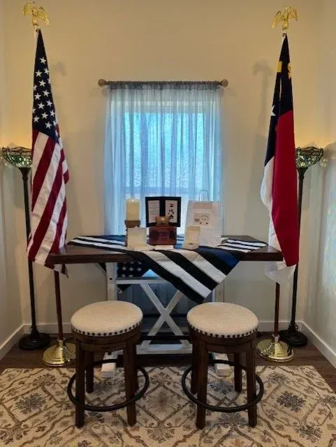 A table with two stools and two american flags in a room.