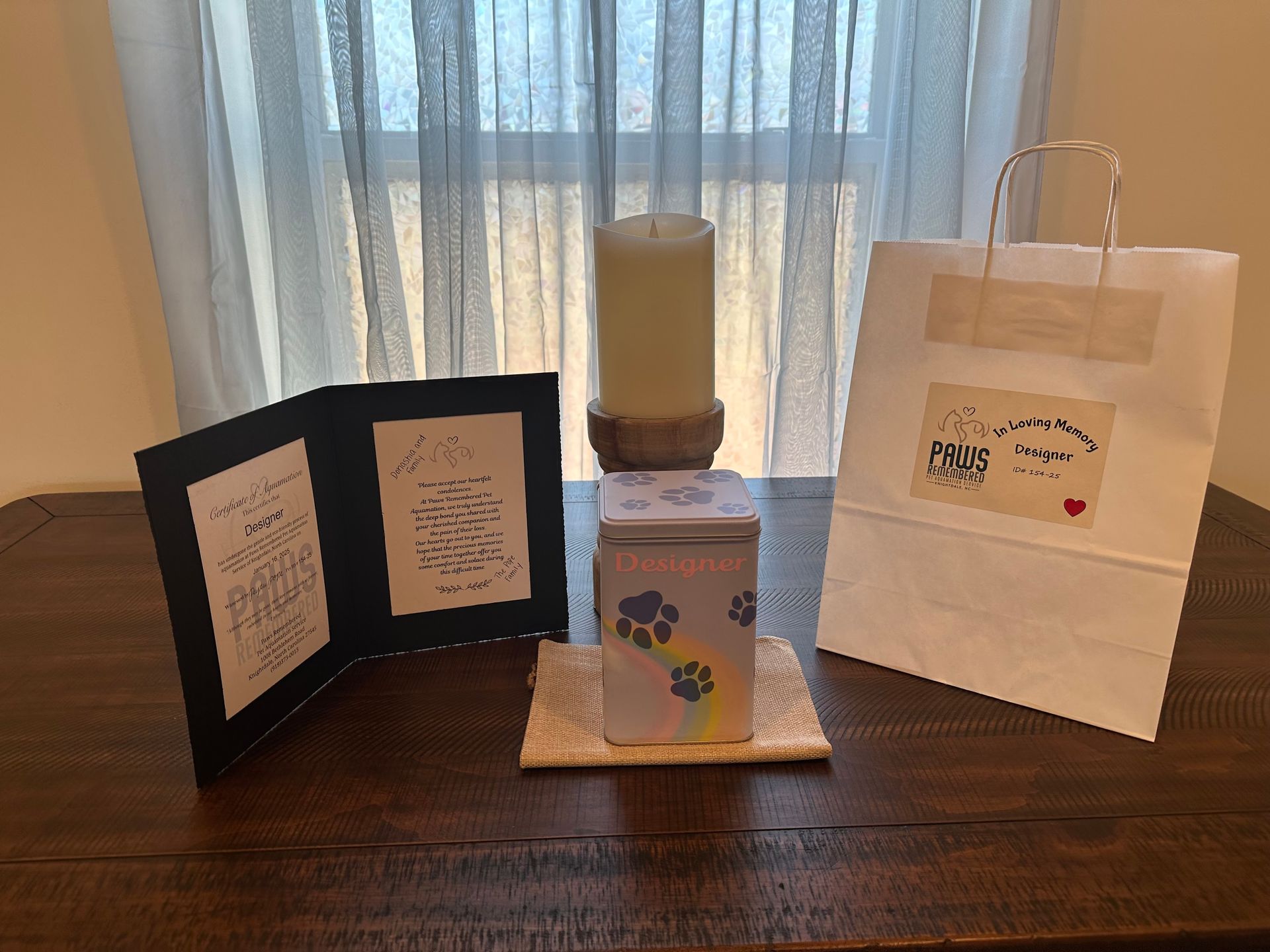 A table with a candle , a box , a card and a bag on it.