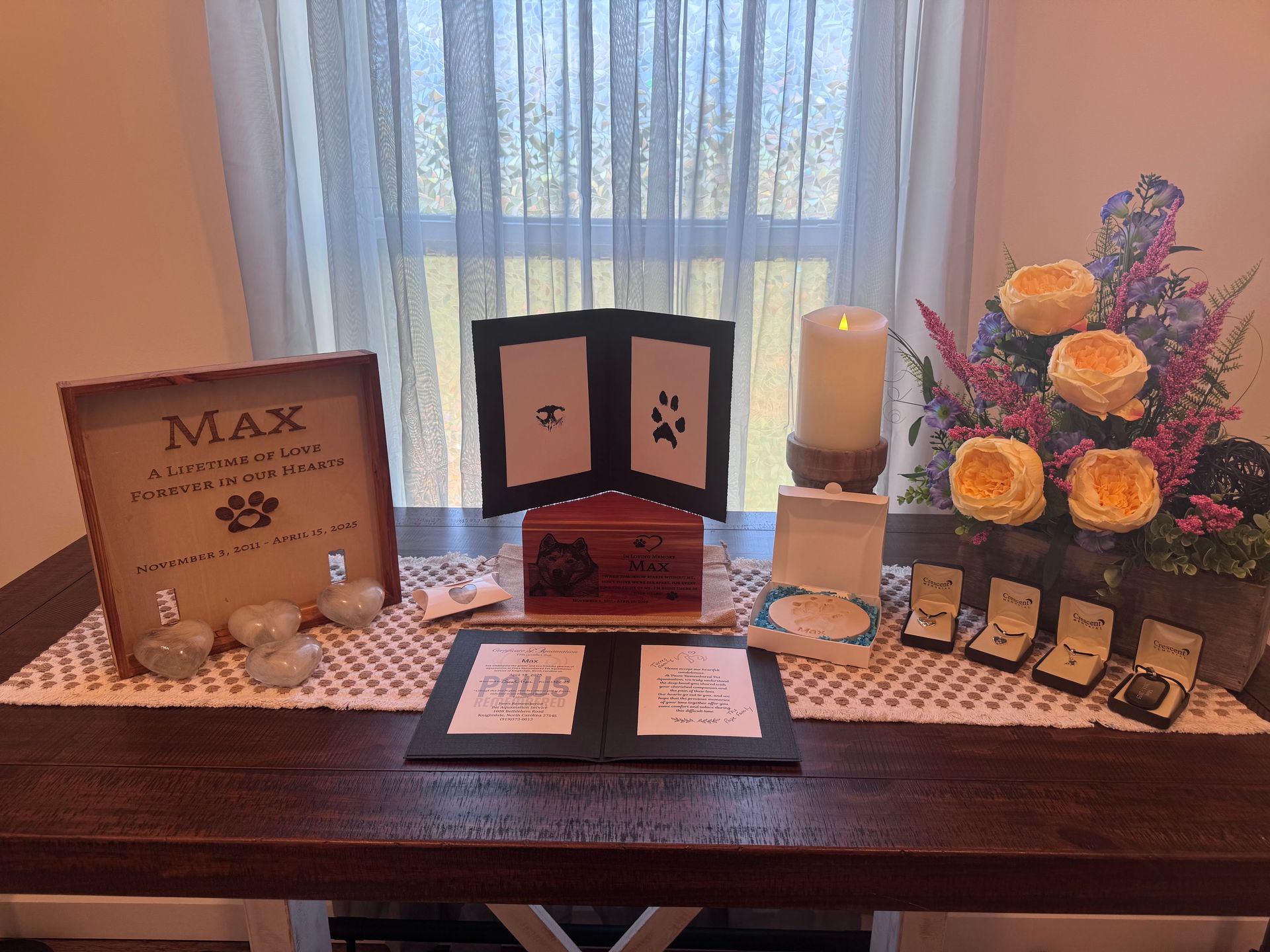 A table with a book , candles , flowers and a box on it.