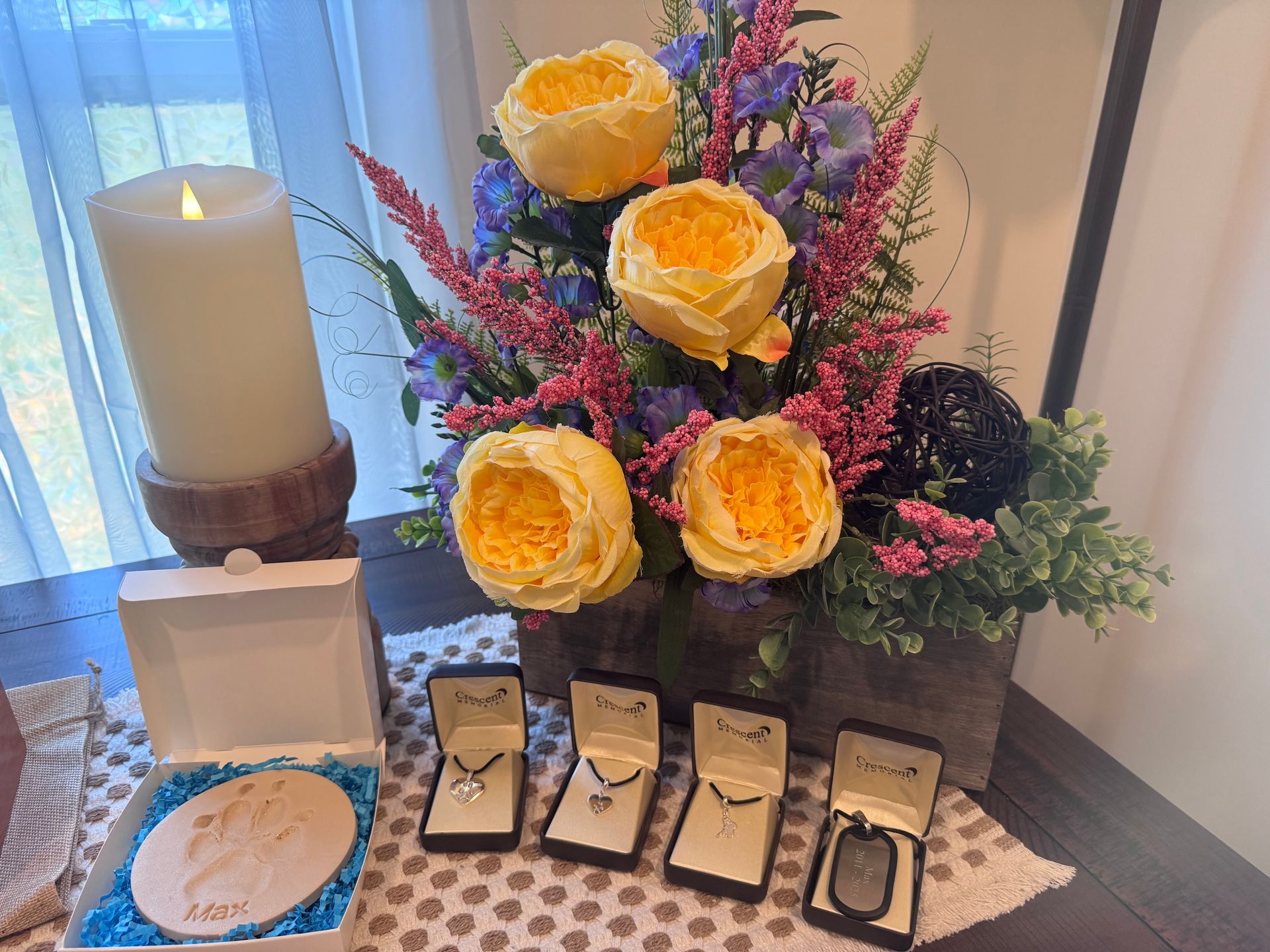 A table with flowers , jewelry , and a candle on it.