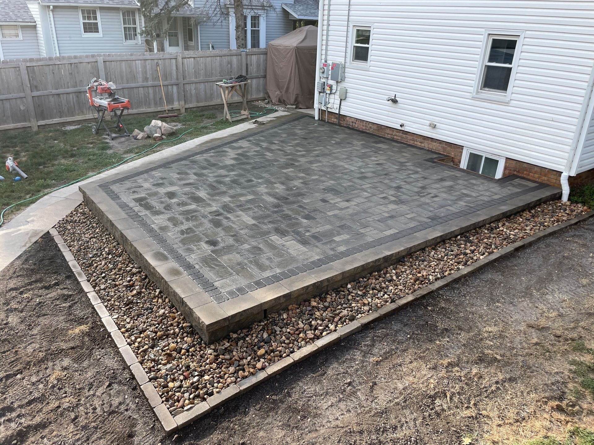 A wooden deck with stairs and a fence in front of a white house.
