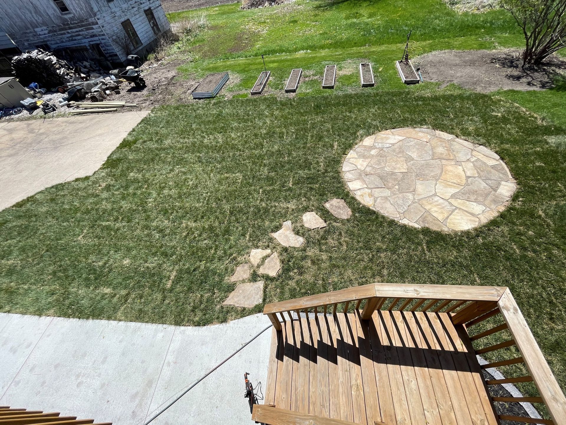 An aerial view of a backyard with a wooden deck and stairs leading up to it.