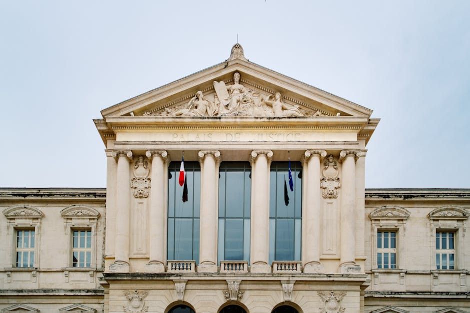 Façade classique d'un bâtiment gouvernemental avec colonnes et drapeaux sous un ciel bleu clair