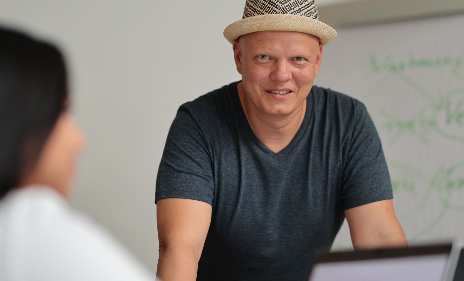 Daniel Docter Gründer der Agentur digitalanders lächelt eine Person vor einem Whiteboard an.