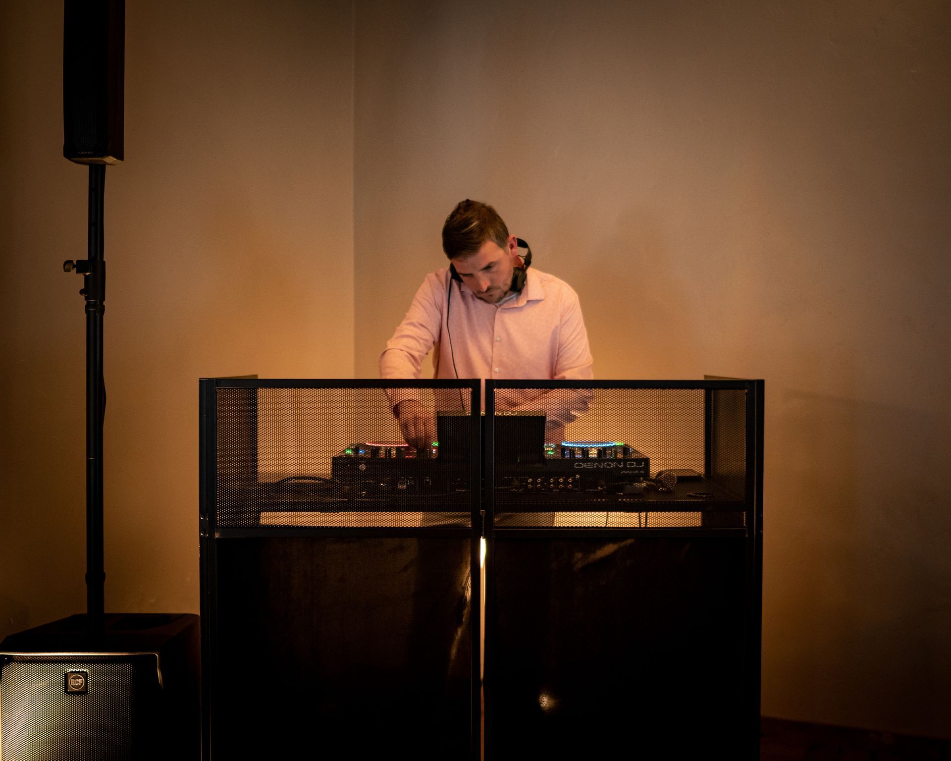 A man is playing music on a dj set in a dark room.