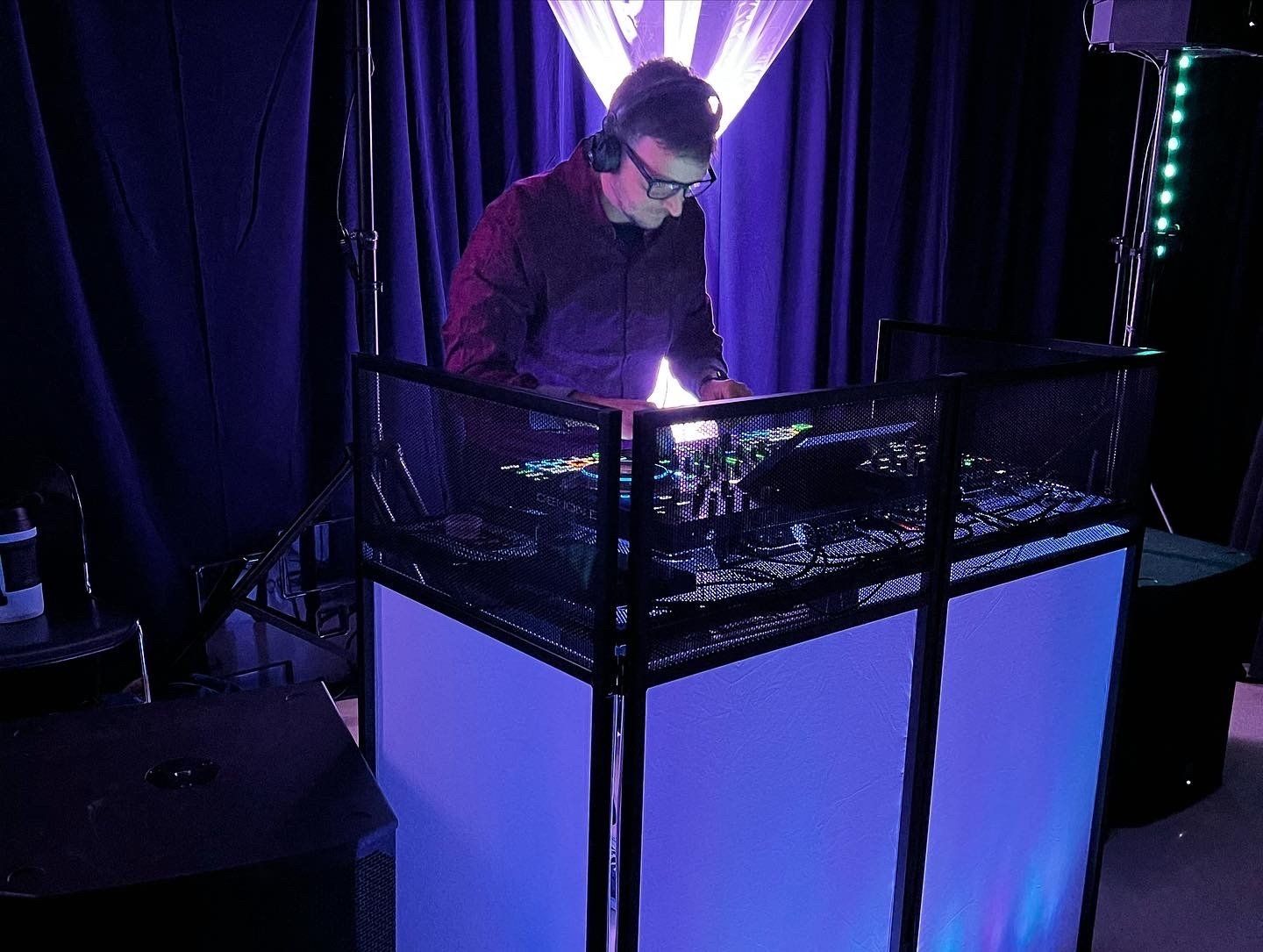A man wearing headphones is playing music on a turntable in a dark room.