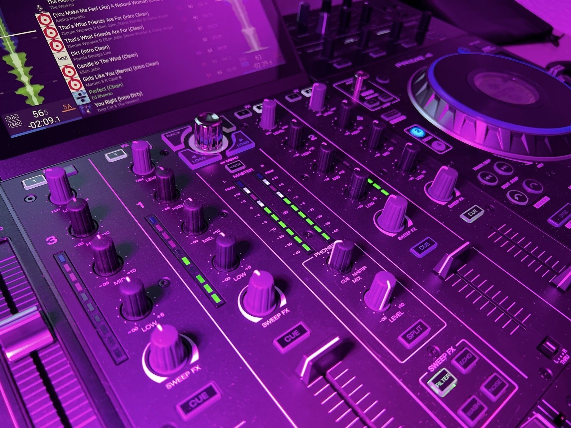 A close up of a dj mixer with purple lights on it.