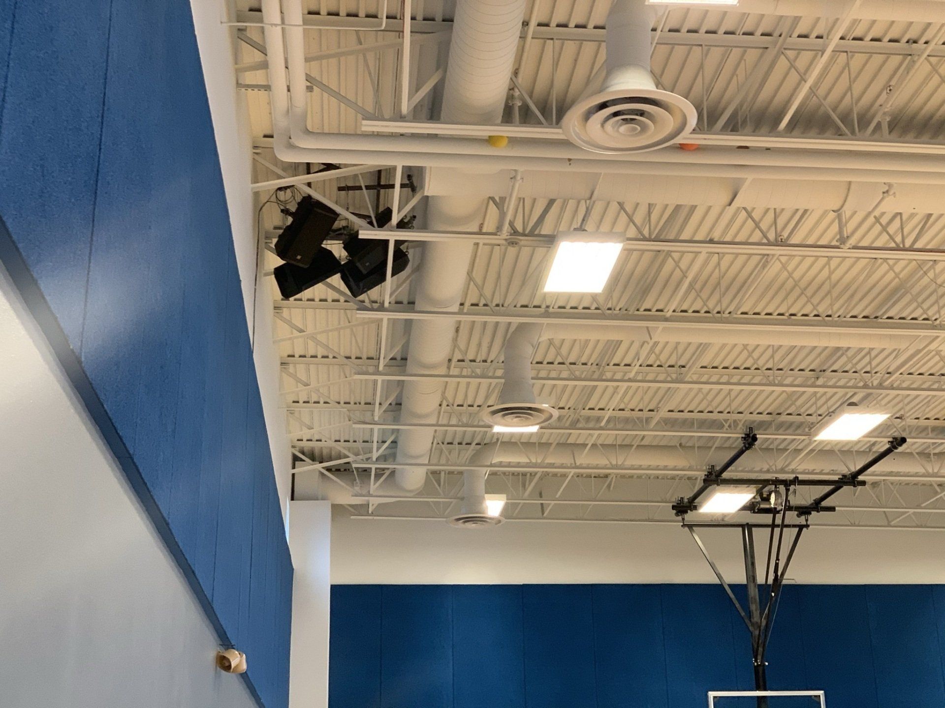 A basketball hoop is hanging from the ceiling of a gym