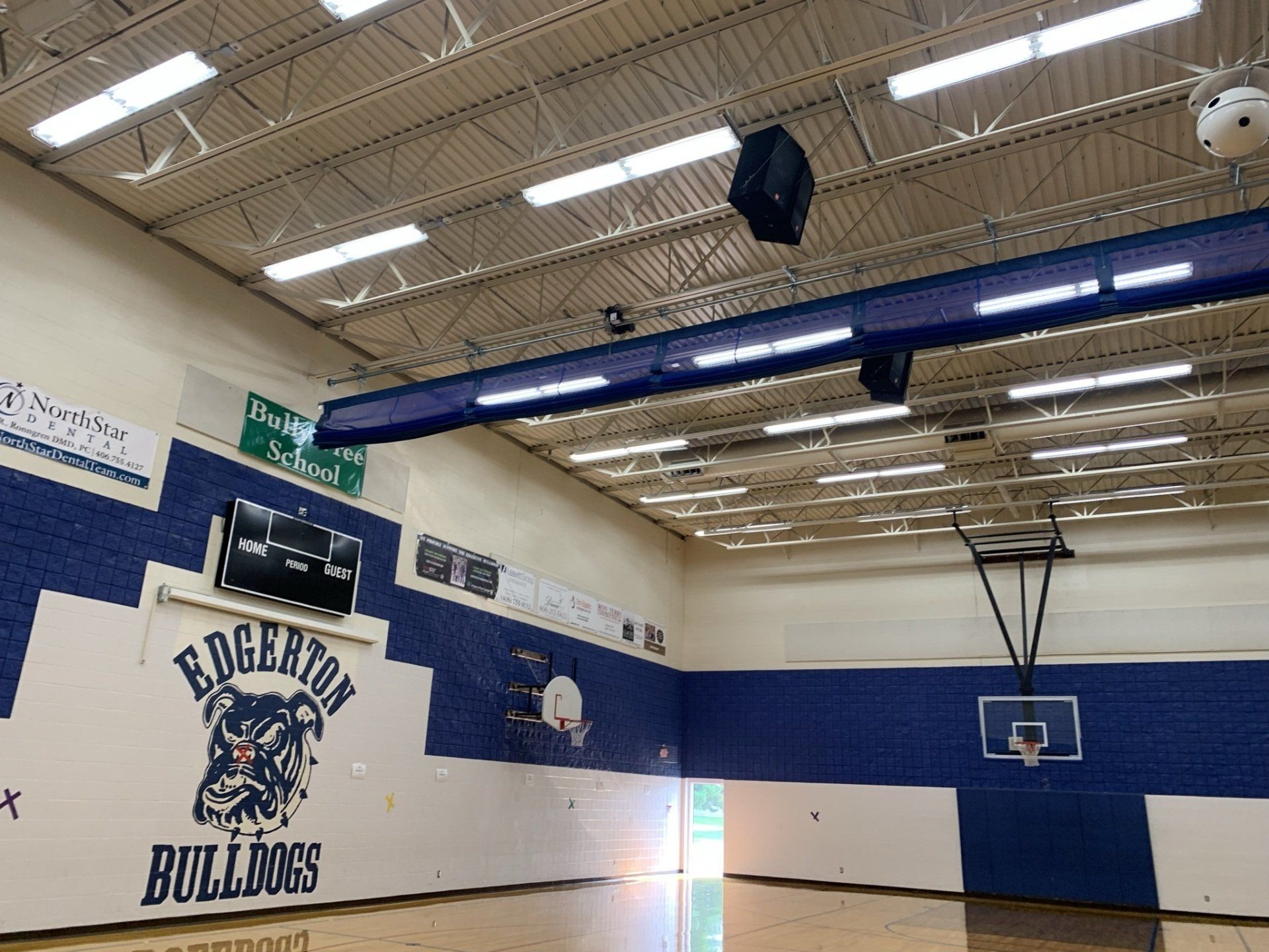 A gym with a basketball hoop and a sign that says ' edgarton bulldogs ' on it.