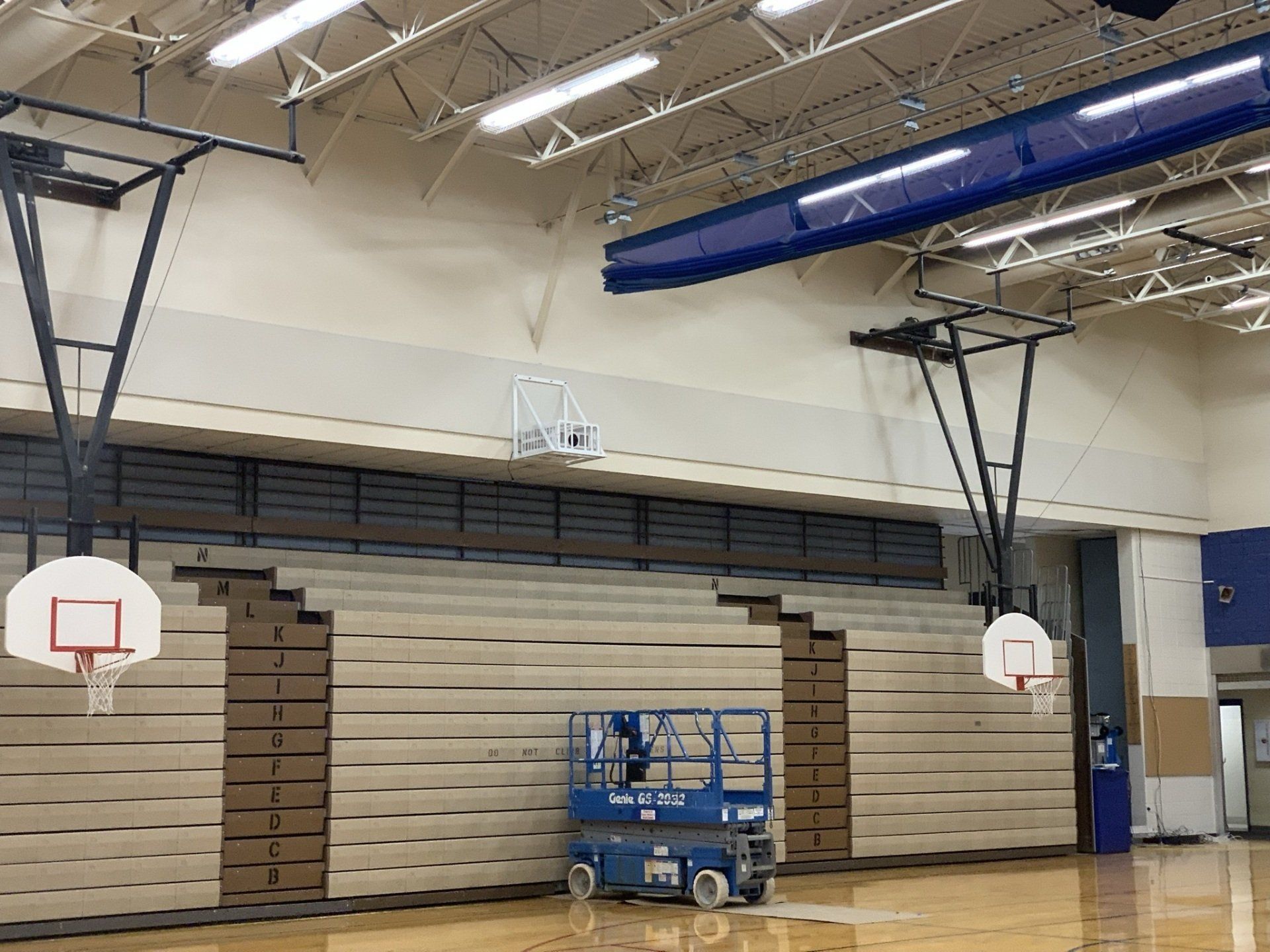 A basketball hoop is hanging from the ceiling of a gym.