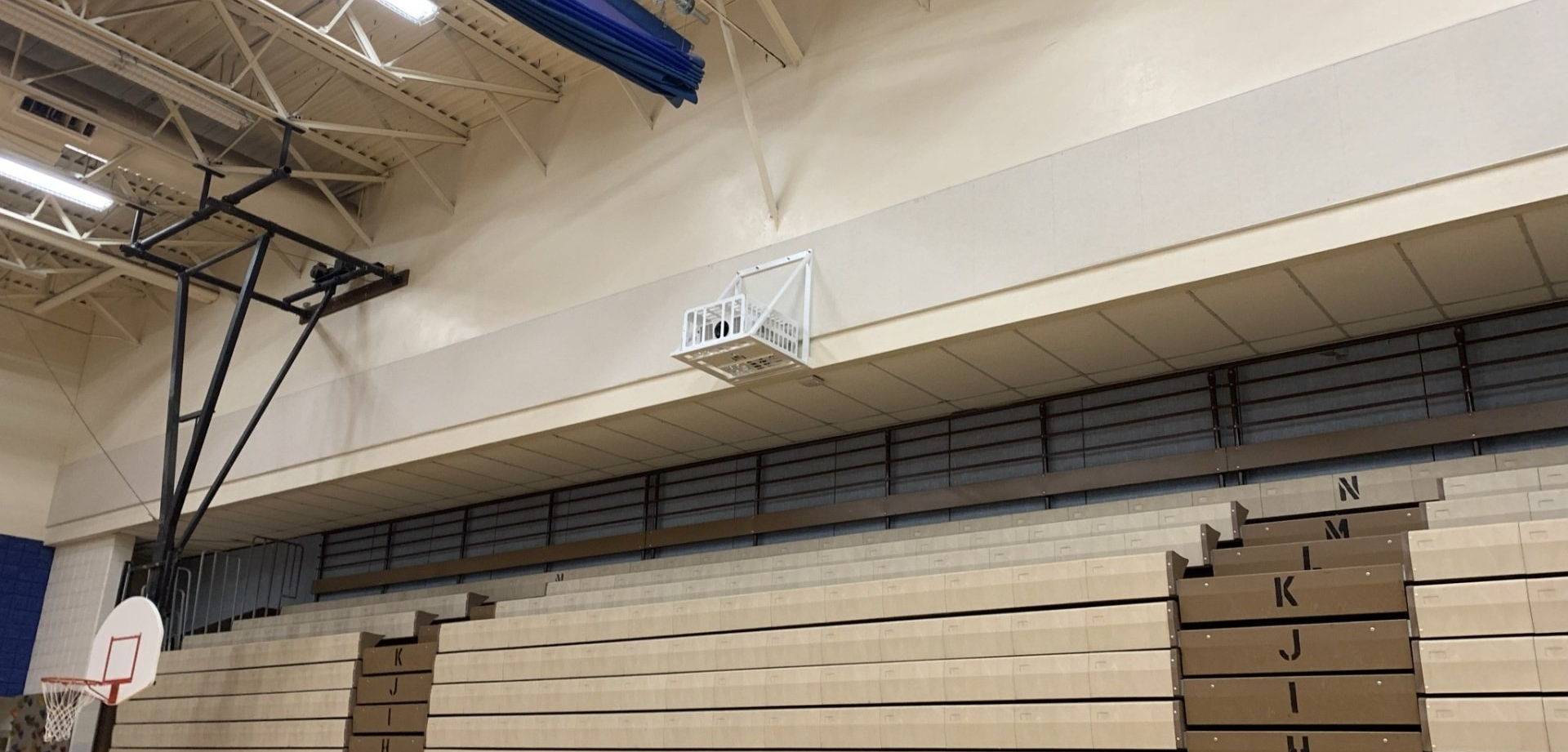 A basketball hoop is hanging from the ceiling of a gym.