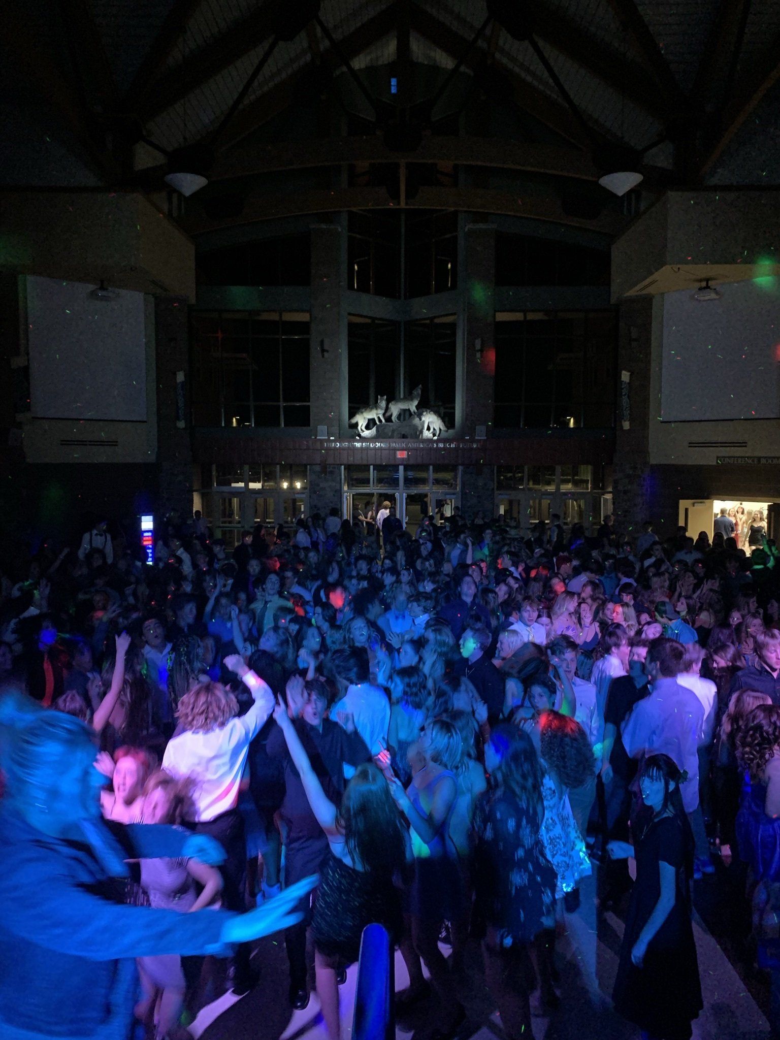 A large crowd of people are dancing in a dark room