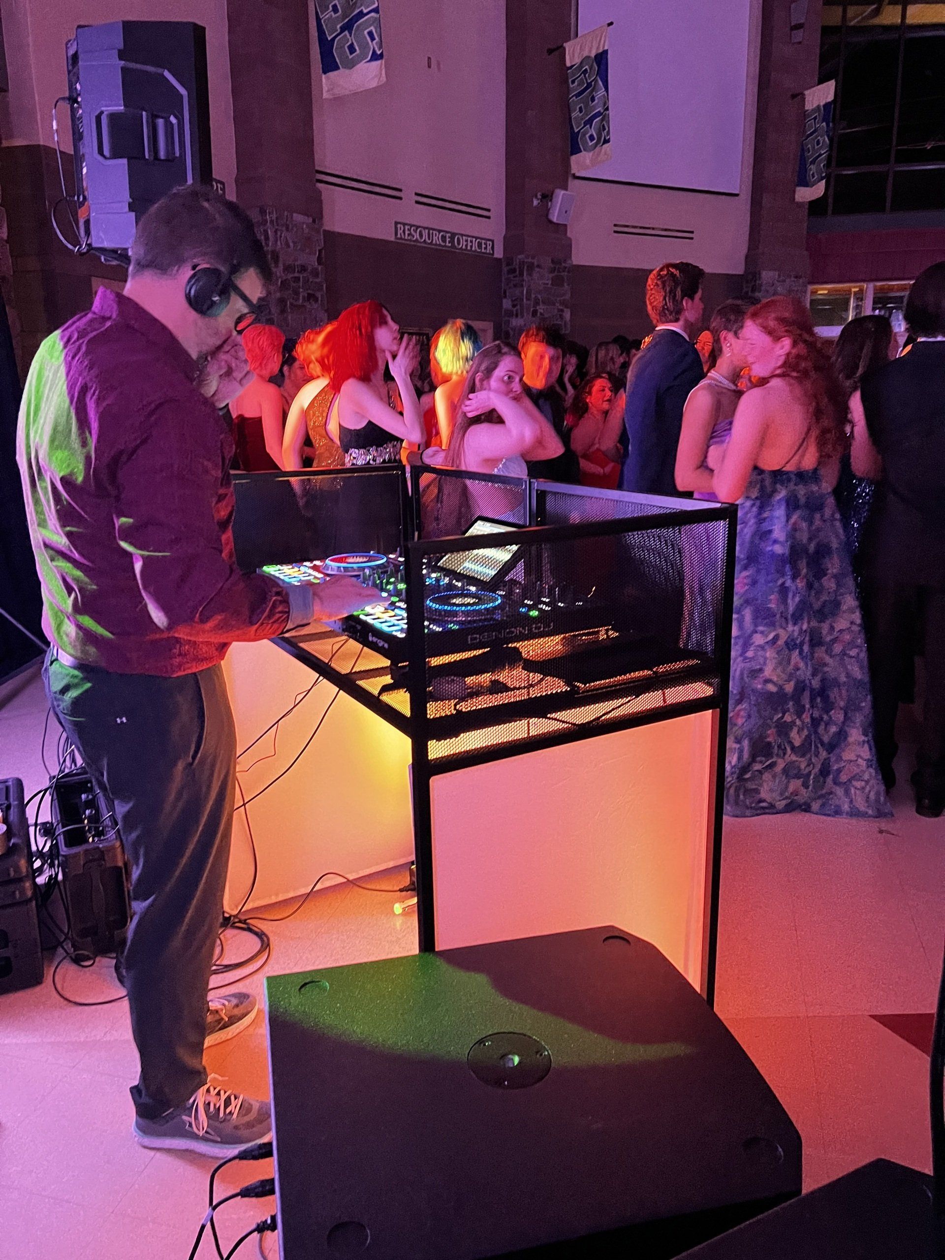 A group of people are standing around a dj booth at a party