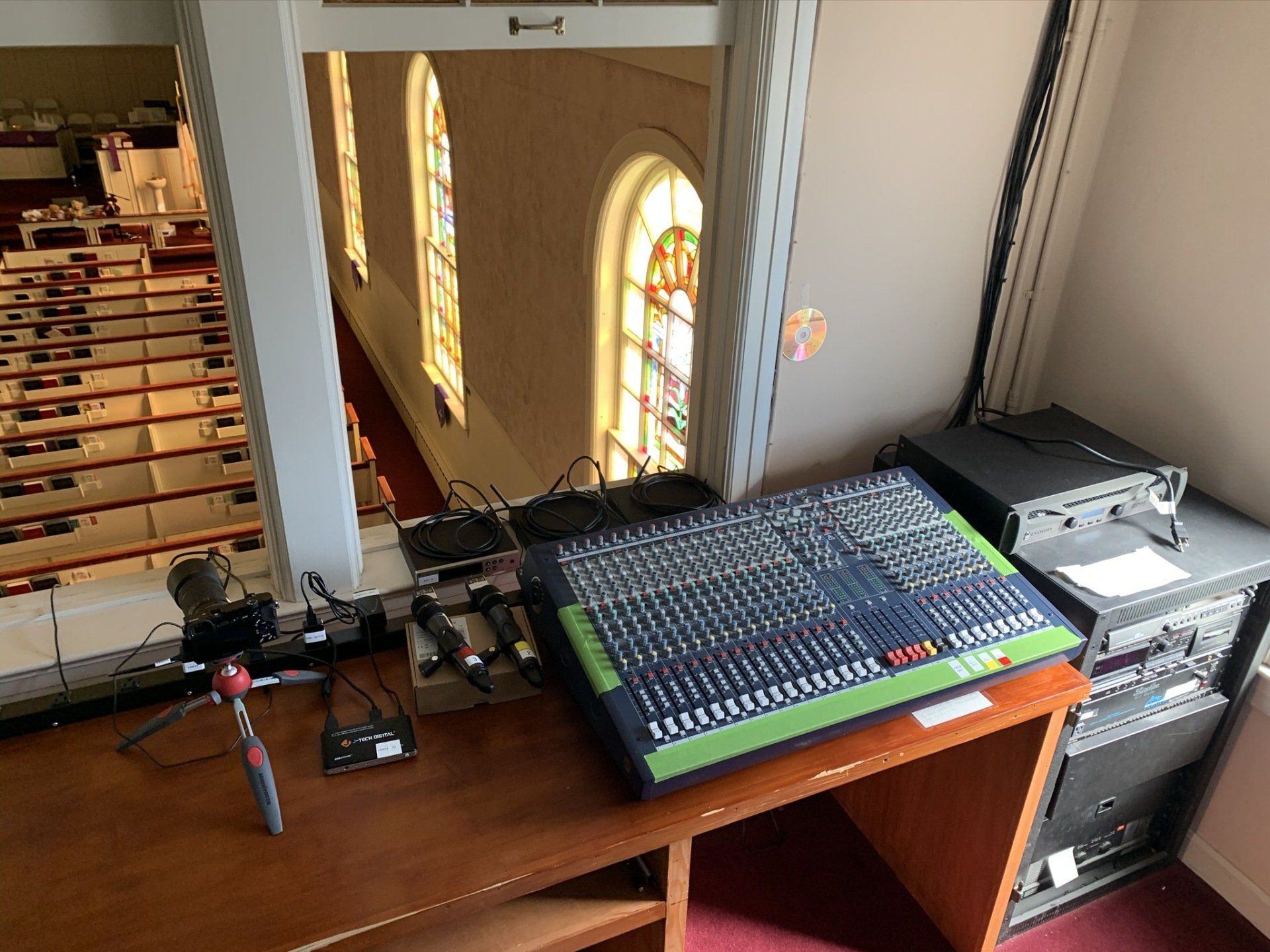 A mixer is sitting on a wooden desk in a church.