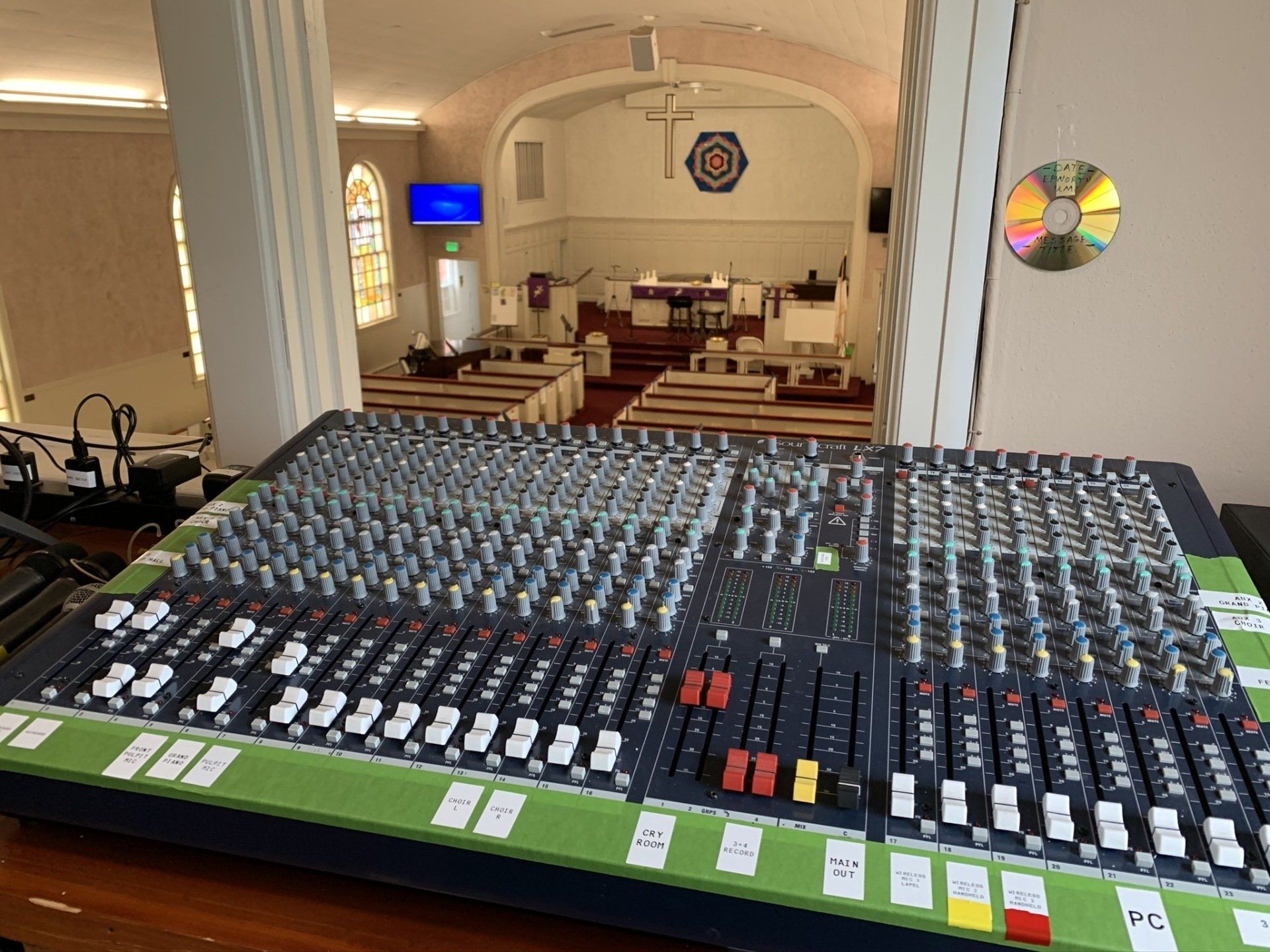A mixer is sitting on a wooden table in front of a church.