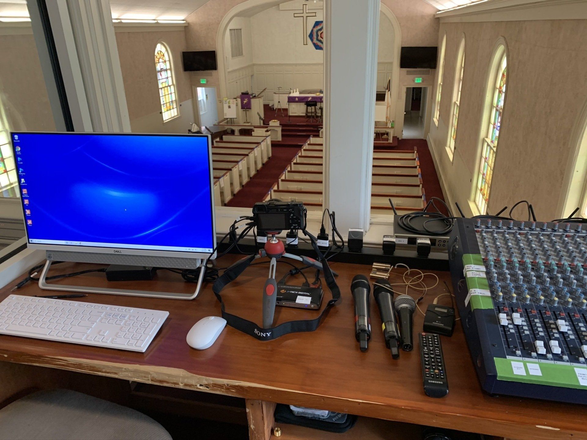A computer monitor is sitting on a wooden desk in a church.