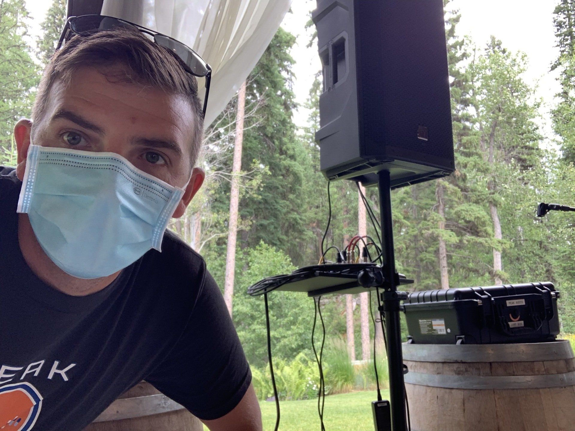 A man wearing a face mask is standing in front of a speaker.