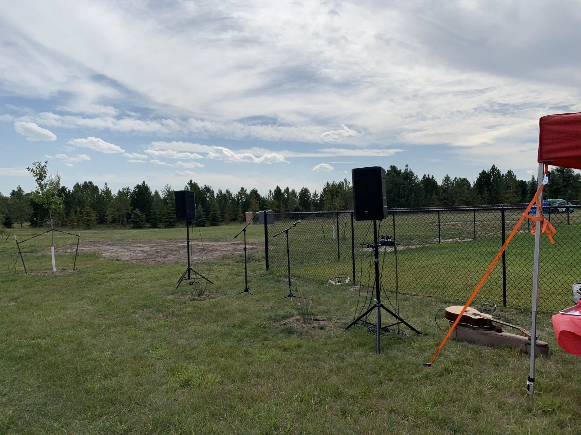 A red tent is sitting in the middle of a grassy field.