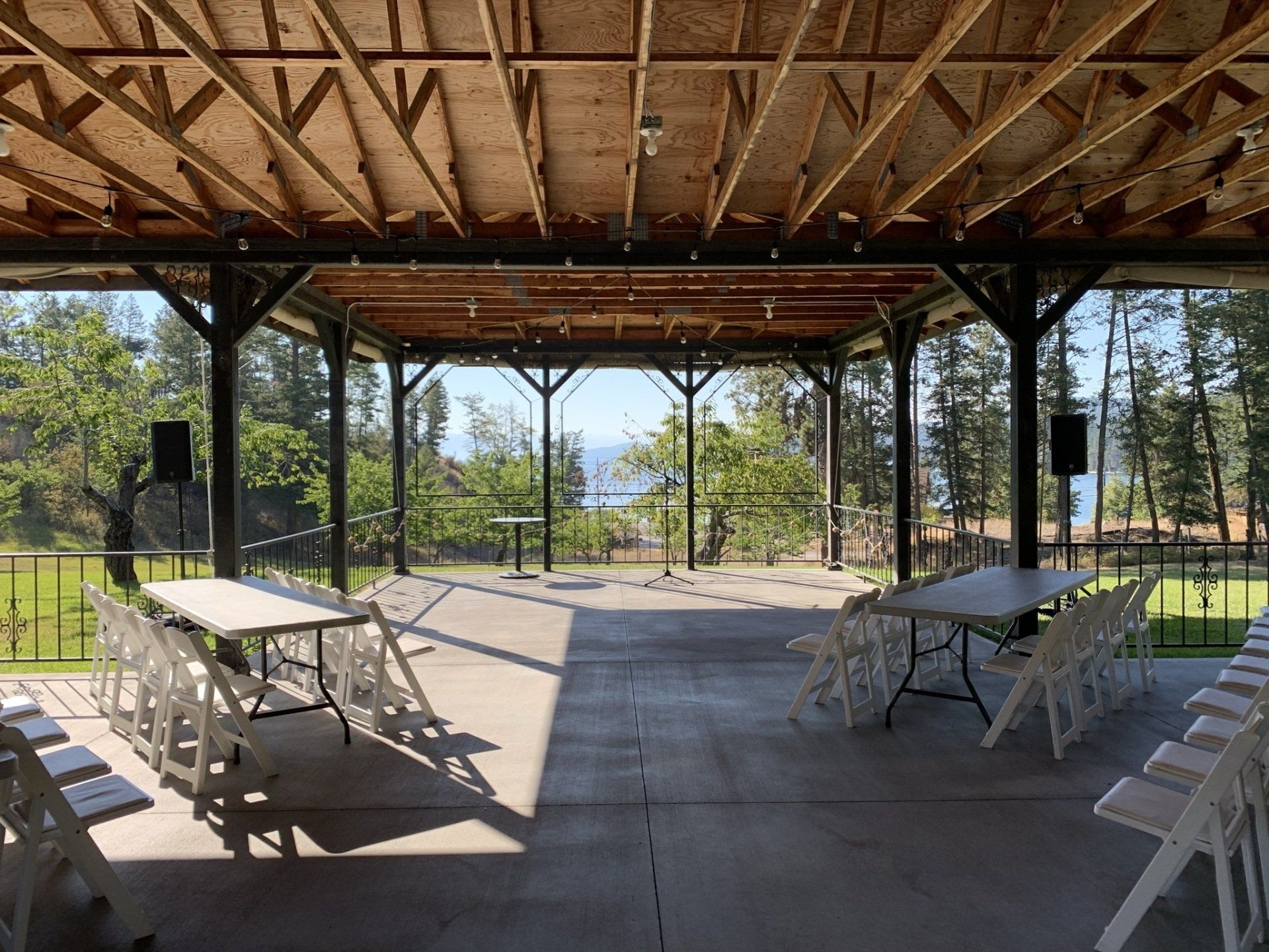 The inside of a pavilion with tables and chairs and a view of a lake.