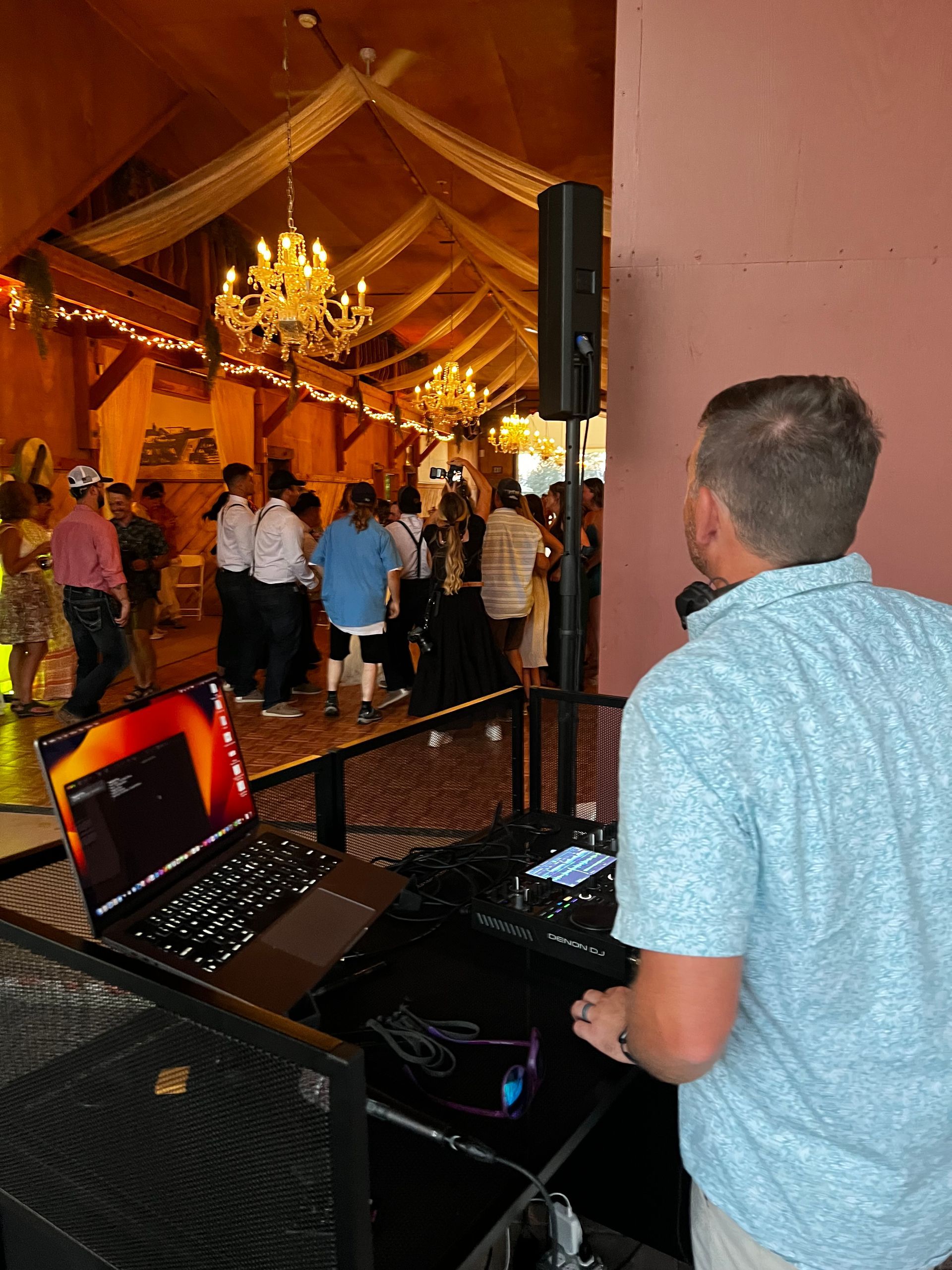 A man is standing in front of a dj booth at a party.