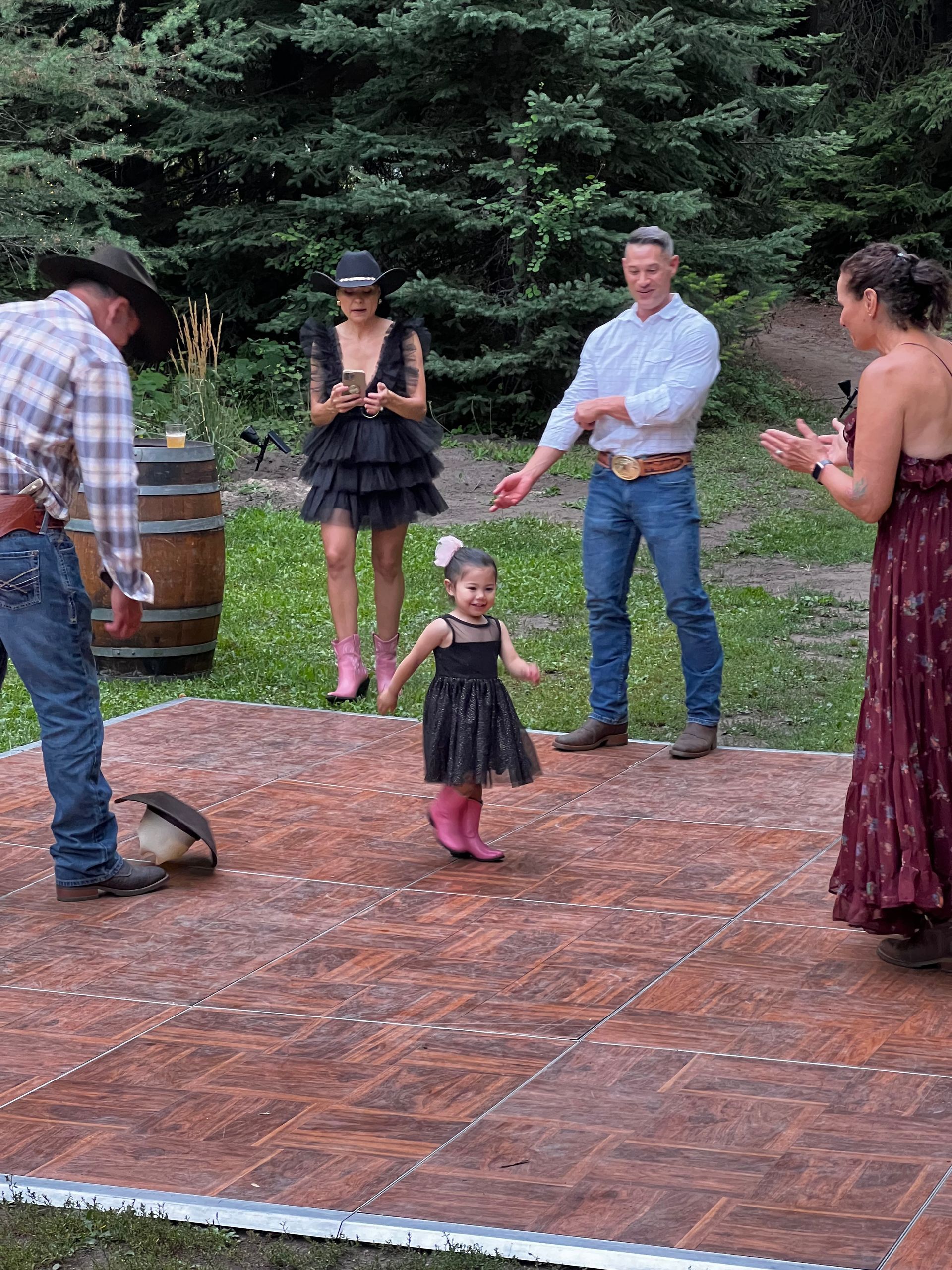 A group of people are standing around a little girl on a dance floor.