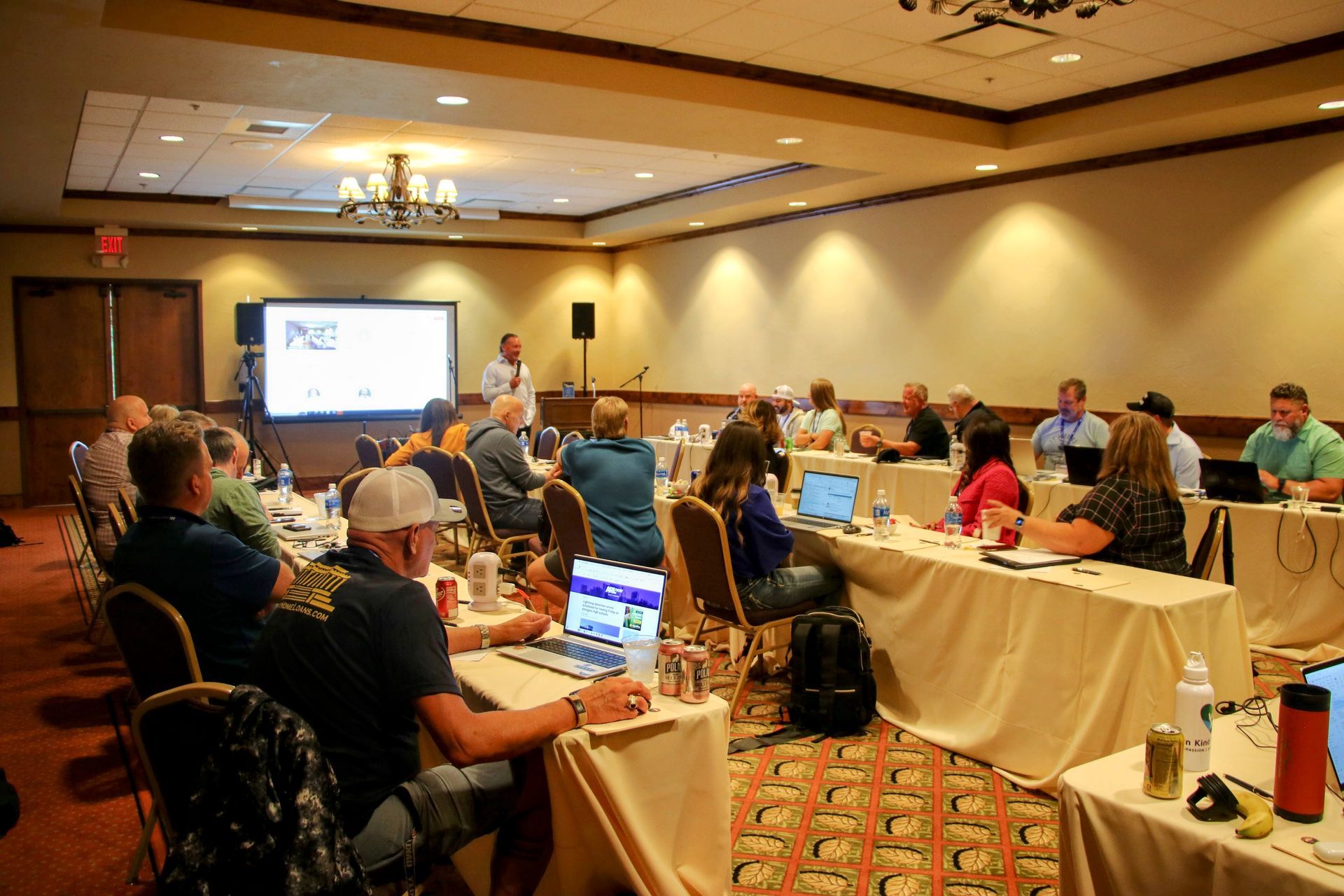 A group of people are sitting at tables in a conference room.
