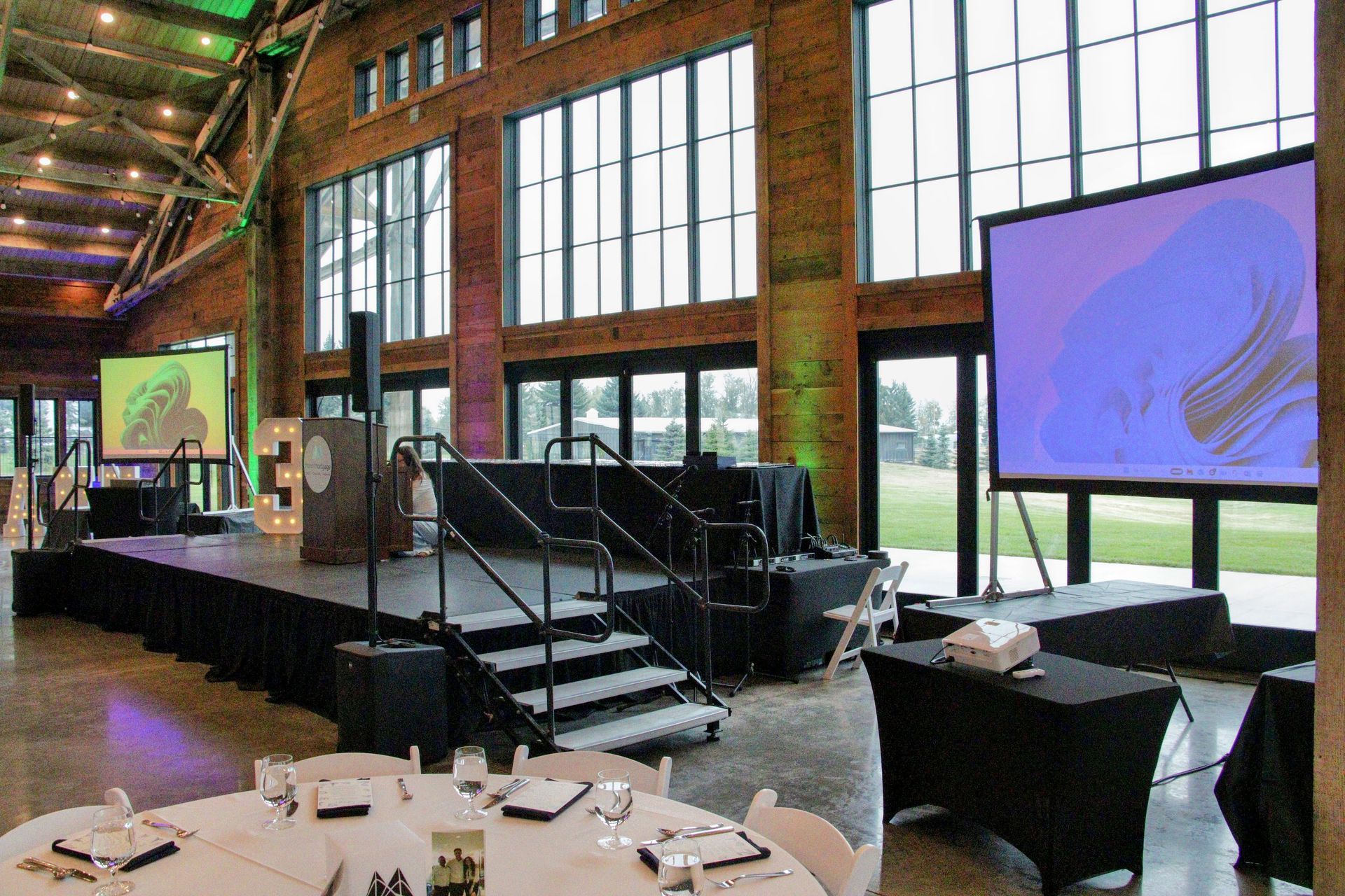 A large room with tables and chairs and a stage.