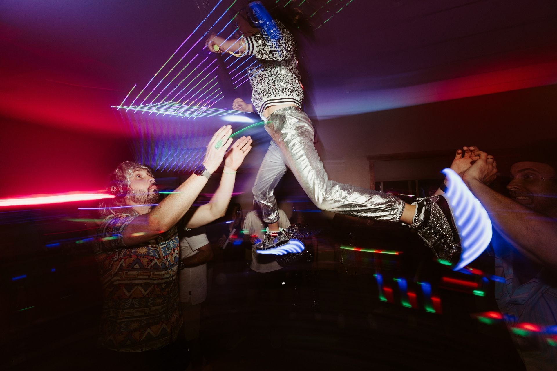 A group of people are dancing in a dark room at a party.