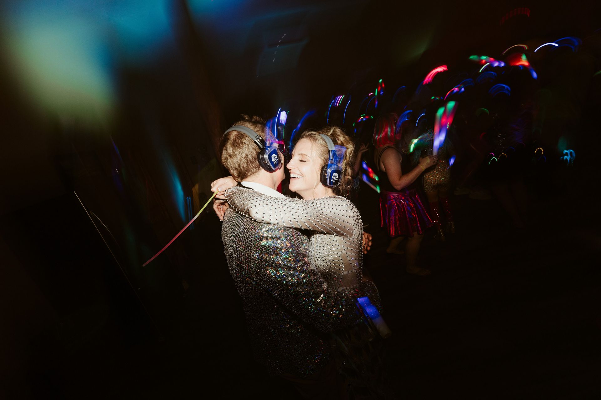 A man and a woman are dancing in a dark room with headphones on.