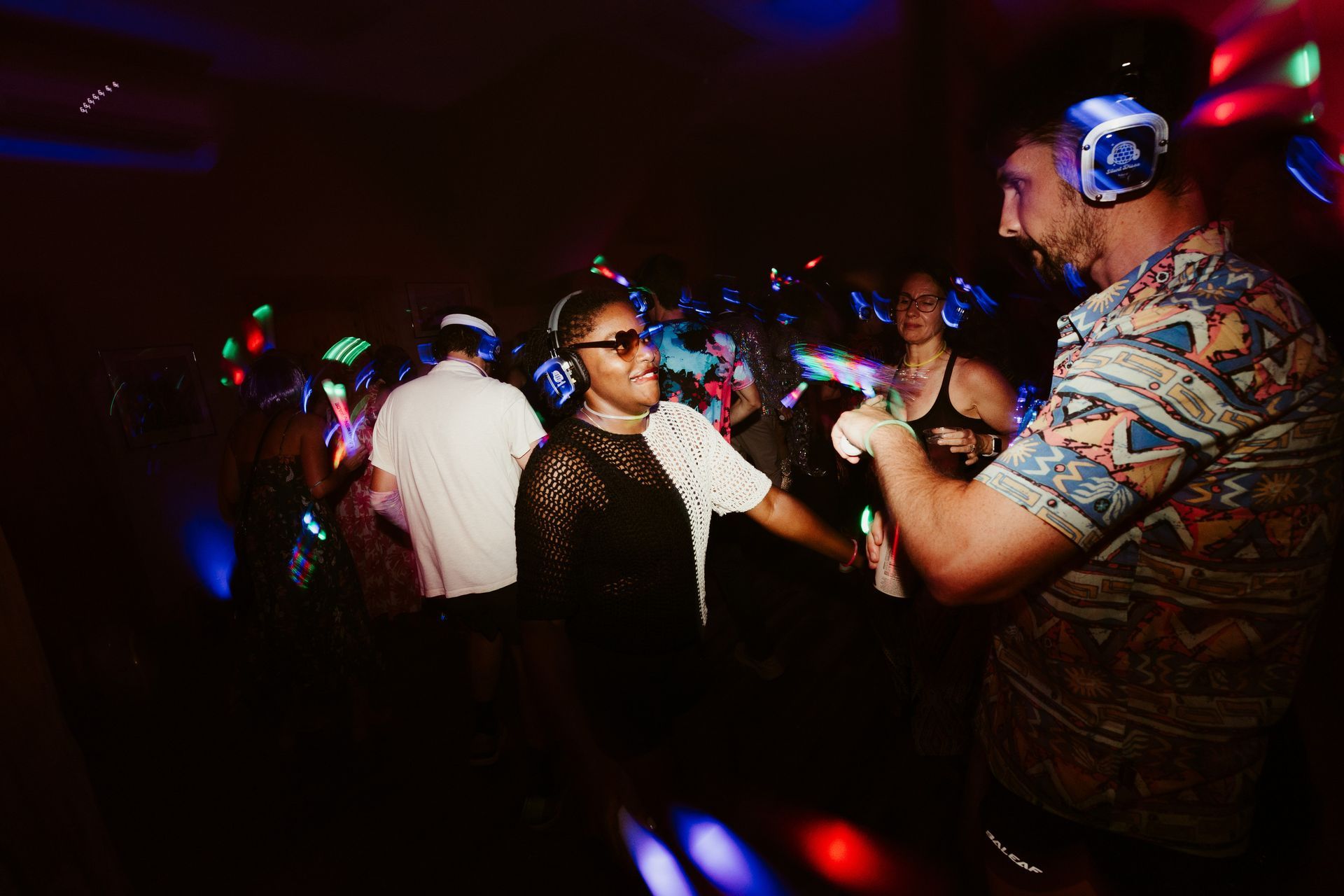 A man wearing headphones is dancing with a woman at a party.